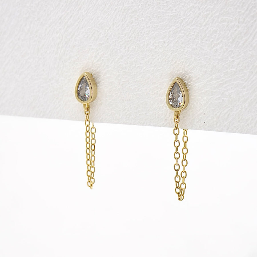 These exquisite earrings feature a delicate teardrop-shaped cubic zircon set in a gold-tone bezel. Each earring is adorned with a fine gold chain that adds a touch of sophistication and elegance to any outfit. Perfect for both casual and formal occasions, these earrings are a versatile accessory that enhances your style with their timeless charm.