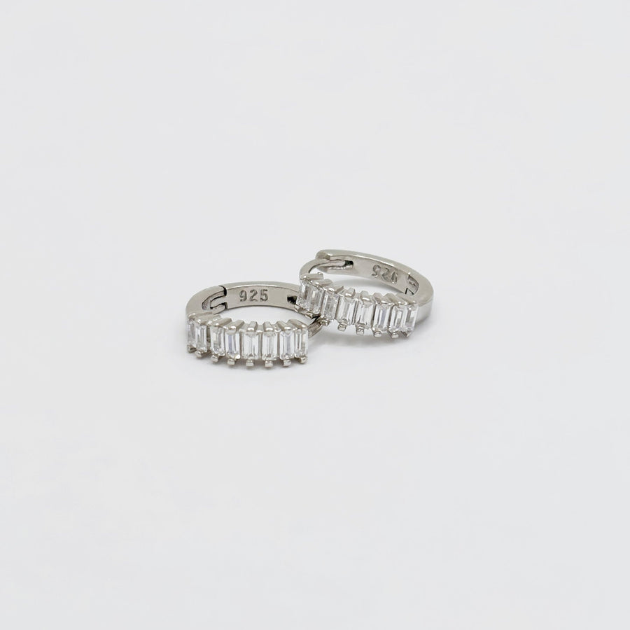 These stunning hoop earrings feature a row of baguette-cut cubic zircon, adding a touch of sophistication to any outfit. Crafted from high-quality materials, these earrings are perfect for both everyday wear and special occasions. 