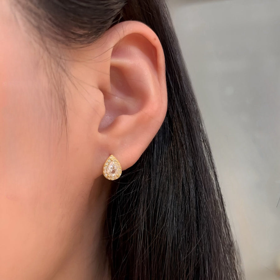 Crafted with elegance in mind, these teardrop-shaped earrings feature a dazzling central cubic zircon surrounded by a halo of shimmering cubic zircon. Perfect for adding a touch of glamour to any outfit