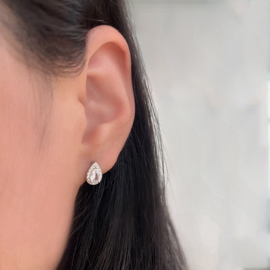 Crafted with elegance in mind, these teardrop-shaped earrings feature a dazzling central cubic zircon surrounded by a halo of shimmering cubic zircon. Perfect for adding a touch of glamour to any outfit