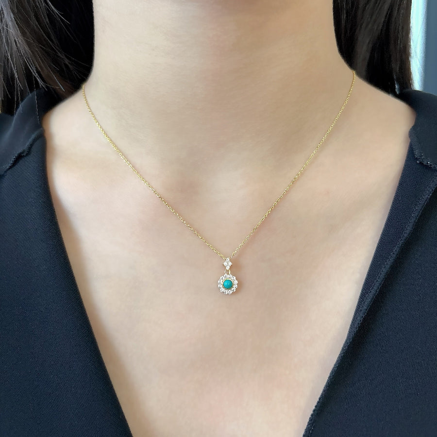 This elegant necklace features a delicate gold chain and a pendant adorned with a central turquoise stone, surrounded by a halo of sparkling cubic zircon. The combination of the vibrant turquoise and the shimmering cubic zircon creates a striking and timeless piece of jewelry. Perfect for any occasion, this necklace adds a touch of sophistication and color to your look, making it a versatile addition to any jewelry collection.