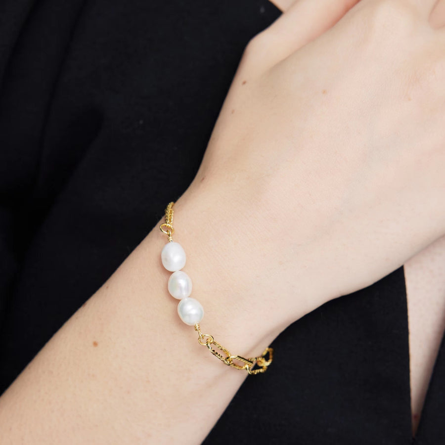 This modern gold vermeil bracelet features a unique combination of bold gold chains and natural baroque pearls, offering a striking contrast of textures. Designed with a toggle clasp for easy wear, this piece adds a statement touch to both casual and formal outfits.