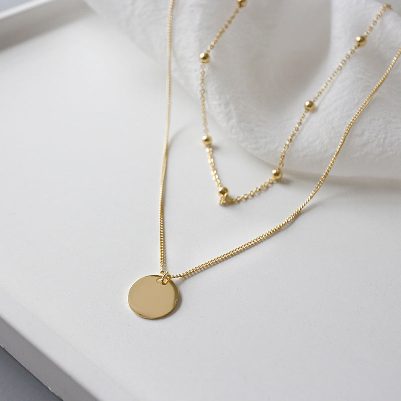 925 Sterling silver necklace. This layered gold necklace combines a sleek coin pendant with delicate bead accents, offering a chic and versatile accessory for any look. Effortlessly elegant, this double-layer design adds depth and charm to your style, perfect for both casual and formal occasions.