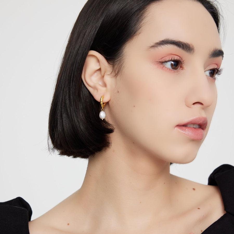 The 925 silver earrings feature a delicate 18K gold-plated twisted hoop paired with an elegant baroque pearl drop. Combining classic charm and contemporary style, these earrings bring sophistication and natural beauty to any look. Perfect for both casual elegance and formal occasions.