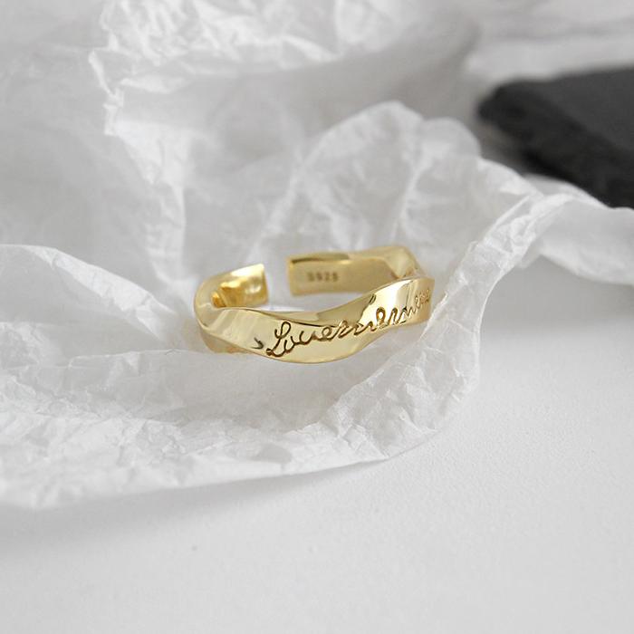 925 silver ring.  A sleek and adjustable gold-tone ring featuring elegant engraved cursive text, perfect for adding a personalized touch to any outfit. Crafted with a modern, twist design, this open-ended ring offers a timeless charm suitable for both casual and formal occasions.